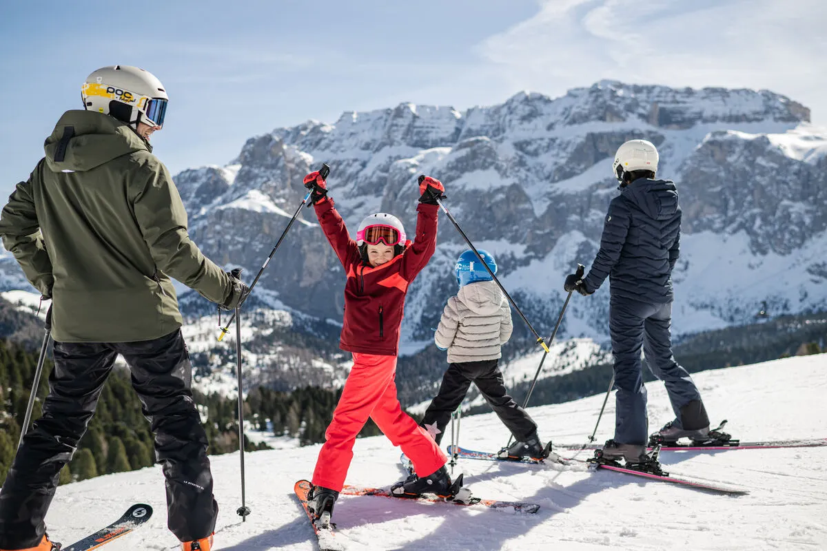 a family on skis as one child turns back to camera smiling with arms in air