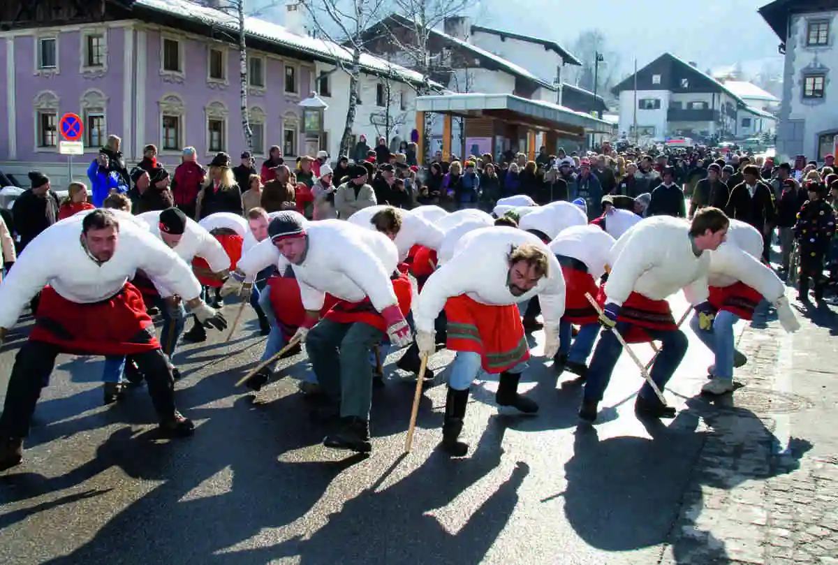 men dressed up in local folklore inspired costume dance in a town street