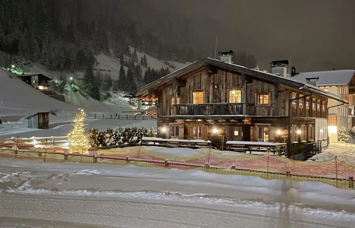 large wooden chalet covered in snow at night