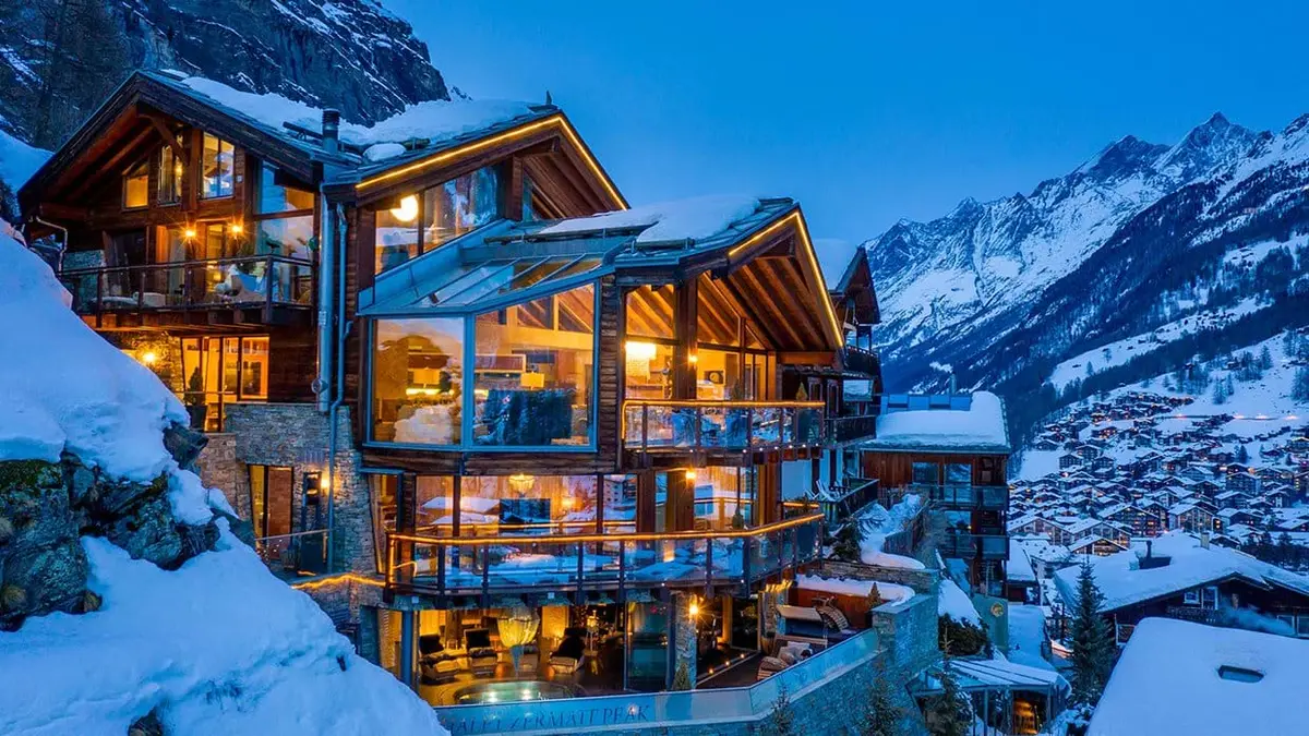 large glass and wooden chalet under snow at night